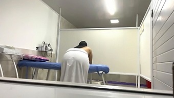 बड़े प्राकृतिक स्तन वाली एक लैटिना नर्स कार्यालय में अपने मरीज के नितंब पर तेल की मालिश करती है।